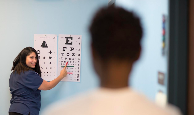 staff providing high school student with eye chart exam