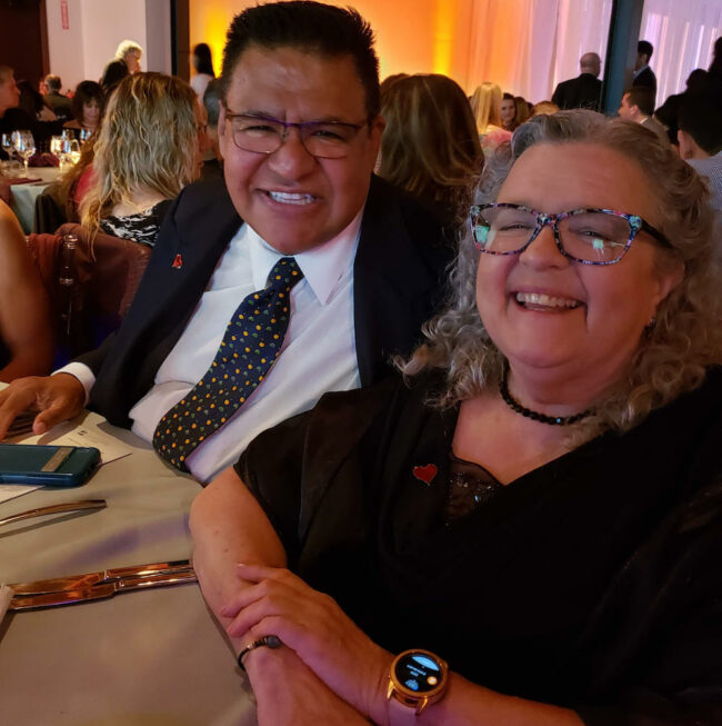 Former board member Roberto Flores with board member Pemba Bayo at a table during a gala event